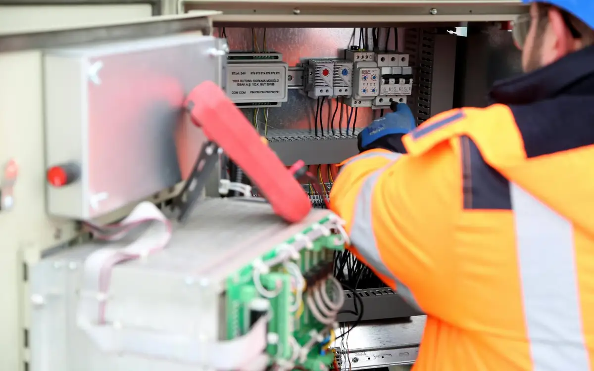 An electrician working on an electrical cabinet